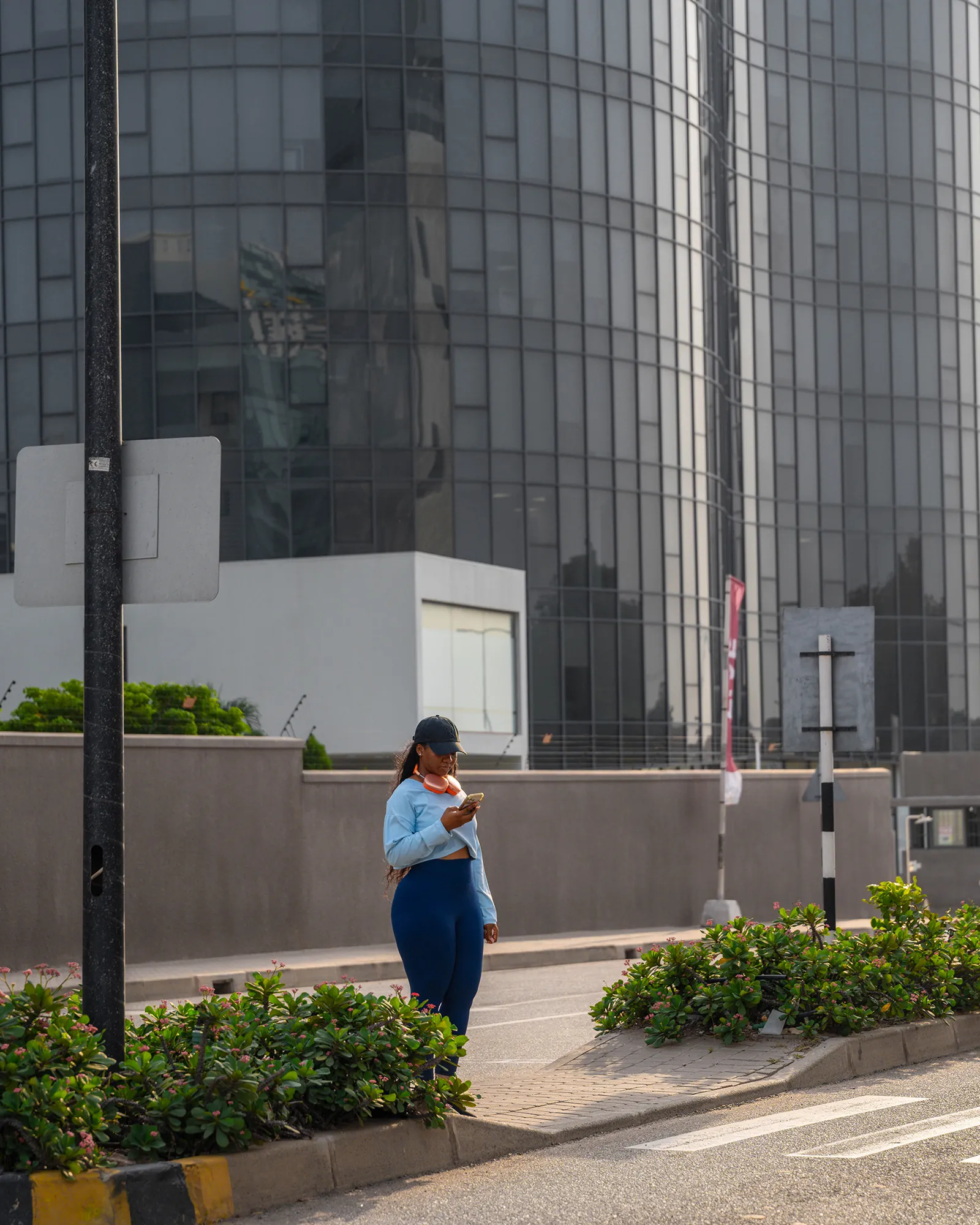 Woman checking phone near glass building
