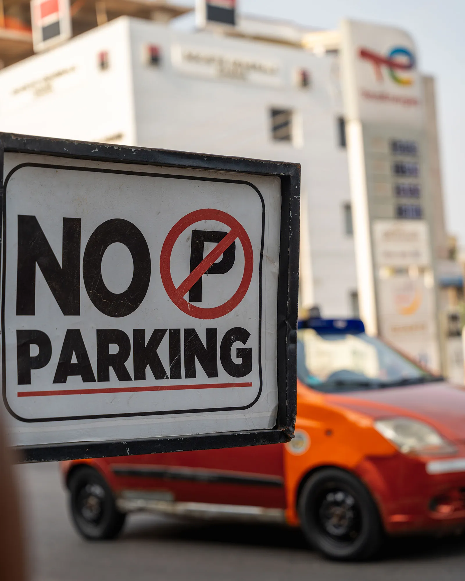No Parking sign and orange car